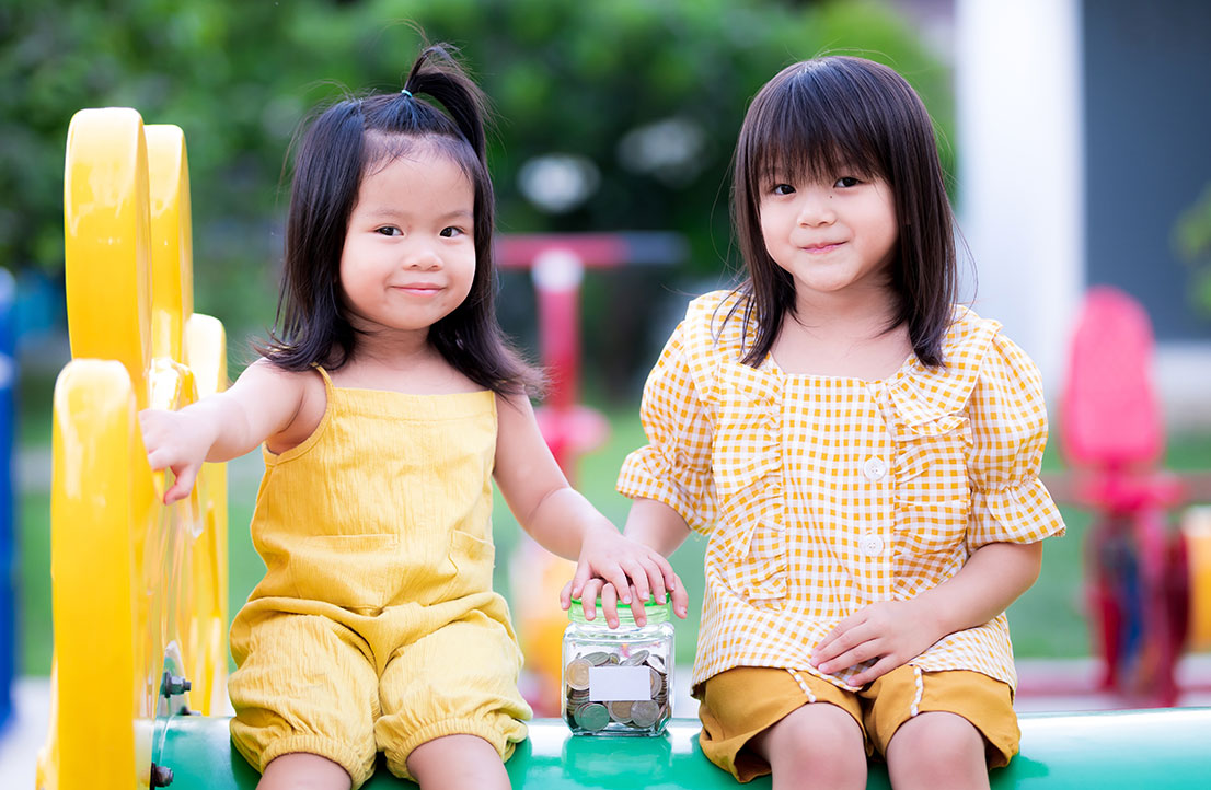 Two young children enjoying outdoor playtime as part of the Early Achievers program, fostering early childhood development and learning.