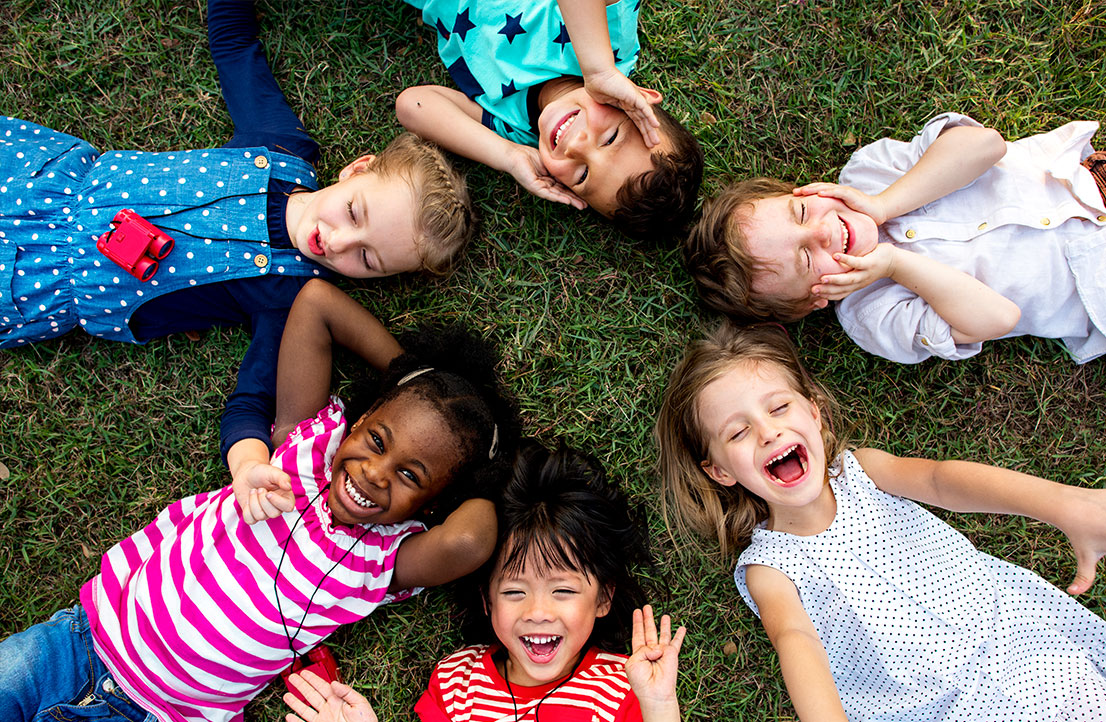 Happy children from diverse backgrounds enjoying outdoor activities together as part of the Early Achievers program, fostering inclusivity and early childhood development.