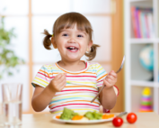 Smiling child enjoying a healthy meal at Early Achievers Preschool Hawaii, promoting nutrition and happiness in a nurturing environment.