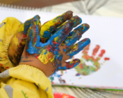 Child painting with colorful hands at Early Achievers Preschool in Hawaii, fostering creativity and hands-on learning.