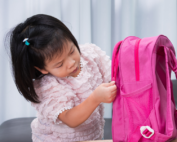 Early Achievers Preschool Hawaii young girl opening pink backpack on first day of preschool, ready for engaging early learning activities
