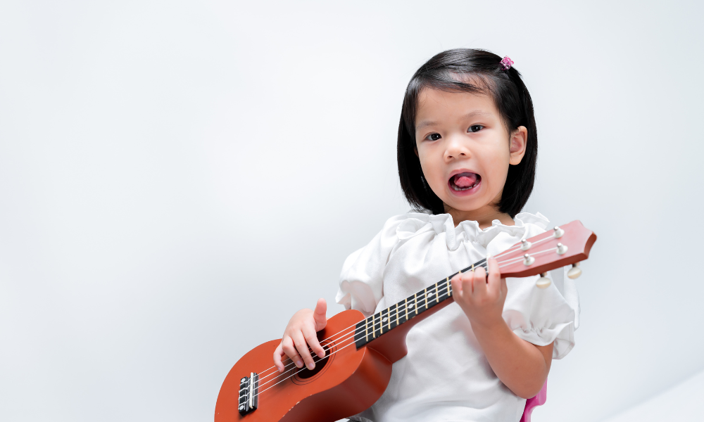 Early Achievers Preschool Hawaii child playing a small guitar, supporting music and movement learning through creative, hands-on play.