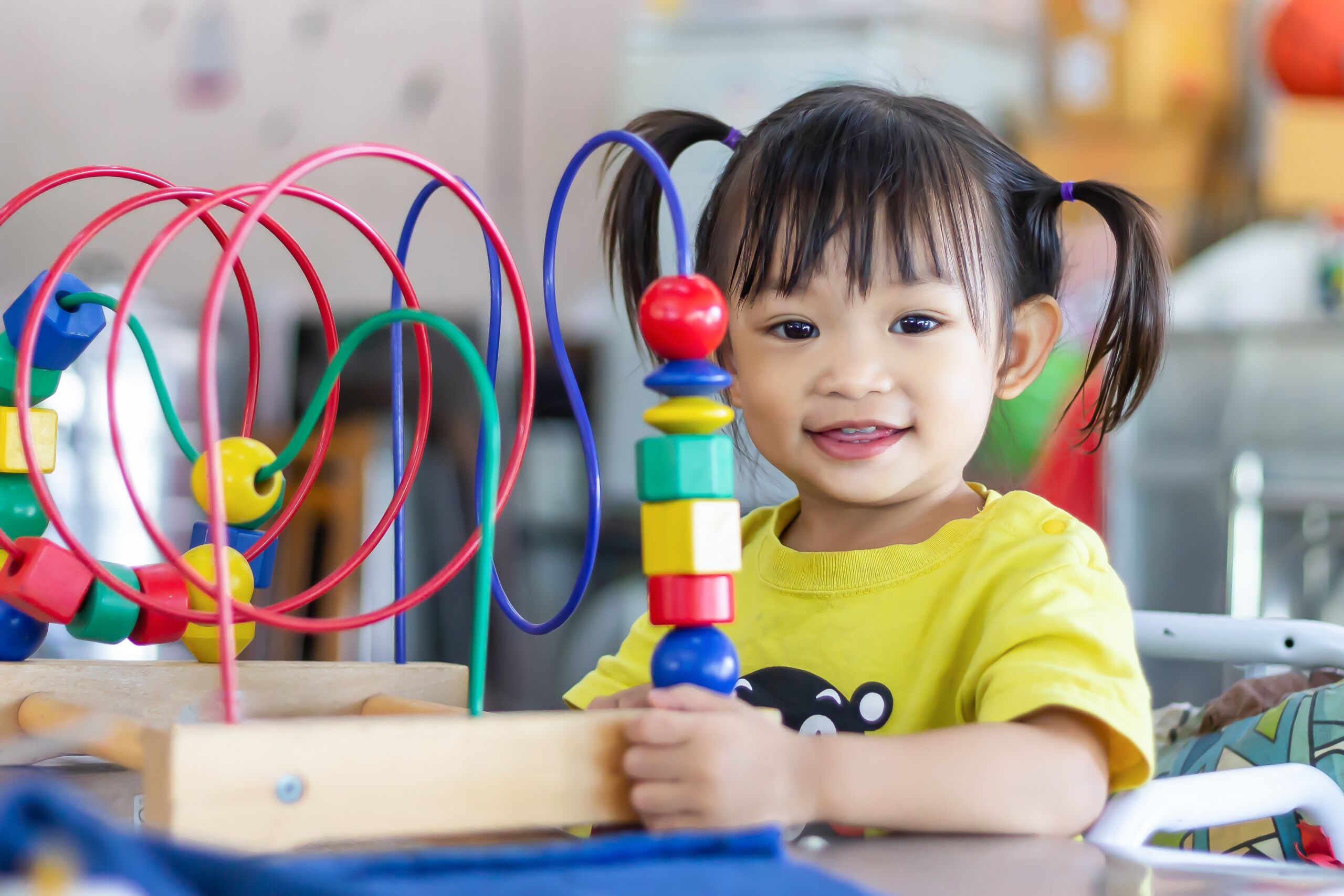 Preschool student engaging with interactive bead maze toy to build problem solving and cognitive skills in early learning environment, Early Achievers Preschool Hawaii