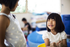 Child smiling and talking with teacher in preschool classroom at Early Achievers Preschool Hawaii supporting communication skills and helping children express their day Child smiling and talking with teacher in preschool classroom at Early Achievers Preschool Hawaii supporting communication skills and helping children express their day